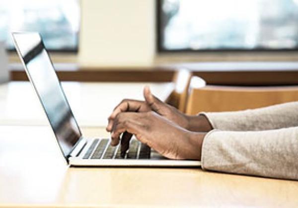 student typing on laptop